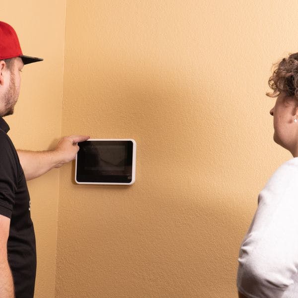 Installation technician showing woman how to operate Vivint control panel