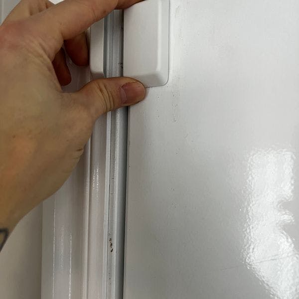 Human hand installing new door sensor