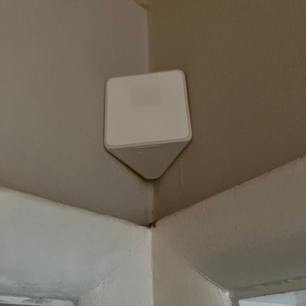 Xfinity home security motion detector installed to corner above doorframes